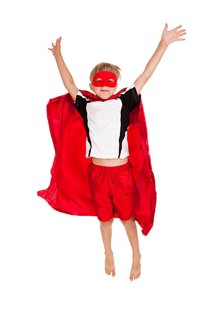 A male child poses in a costume pretending that he is a superhero.