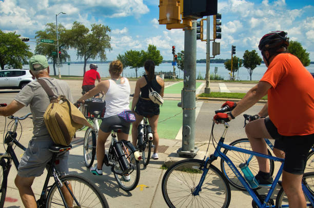Bikes at Crossing in Madison On a Summer day in Madison, WI, bikers wait to cross a busy street on a trail near Lake Monona. lake monona photos stock pictures, royalty-free photos & images