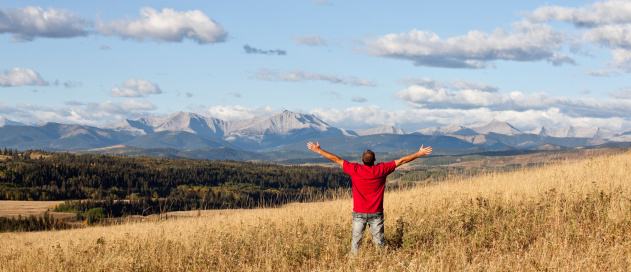 A man with his arms outstretched in a beautiful mountain and prairie scene. Rocky Mountains. Panorama. Fall scenic.