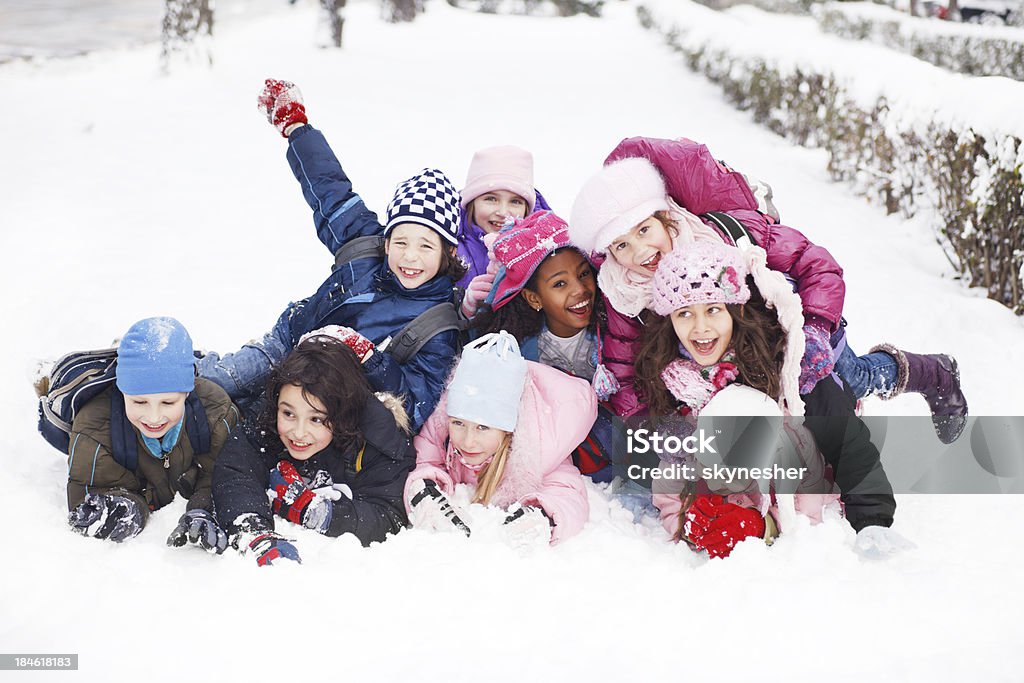 Divertente gruppo di bambini sono sdraiato/a sulla neve. - Foto stock royalty-free di Bambino