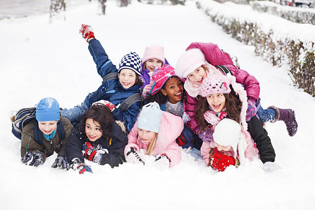 Funny group of children are lying in the snow. Large group of children are lying on top of each other on the snow.   children in winter stock pictures, royalty-free photos & images