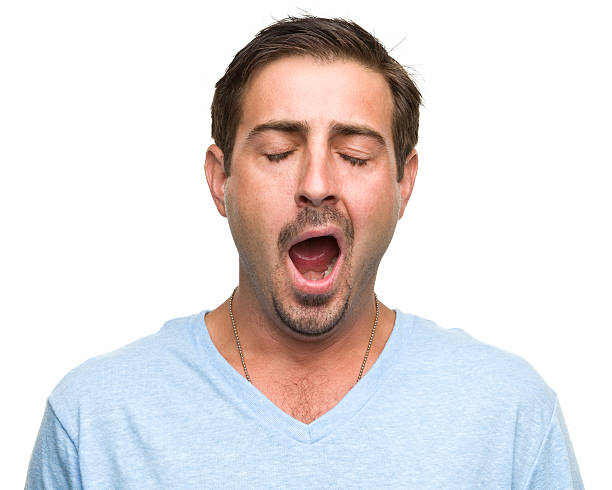 A tired man wearing a blue top is yawning  Portrait of a man on a white background. http://s3.amazonaws.com/drbimages/m/as.jpg yawning stock pictures, royalty-free photos & images