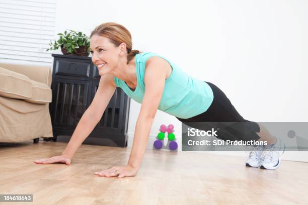 Young Woman Looking Up While Doing Pushups In Living Room Stock Photo - Download Image Now