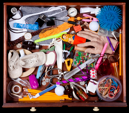 Junk Drawer with miscellaneous objects, Including, Baby Shoes Elastic Bands, Pencils, Compass, New Years Eve Party Blower, Fake Hand, Cellophane Tape, and More. Image shot with, Canon 5D Mark2 , 100 ISO, 24-115mm lens and studio strobes.