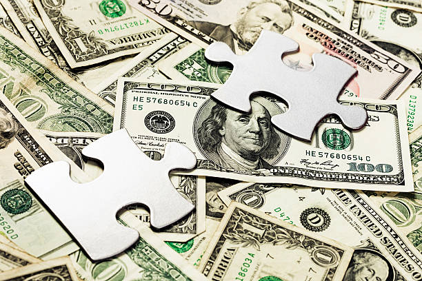 istock Silver jigsaw pieces on a background of many US dollars 184619955