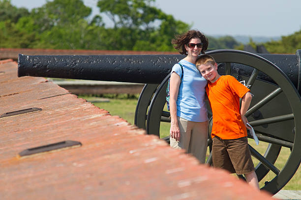 Mother and Child Tourists With Civil War Canon, Ft. Pulaski Shown here are a thirty something year old female tourist and her ten year old son near a Civil War canon on the grounds at Ft. Pulaski National Park on Tybee Island. civil war photos stock pictures, royalty-free photos & images