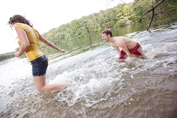 istock Young man splashing woman in lake 184621247
