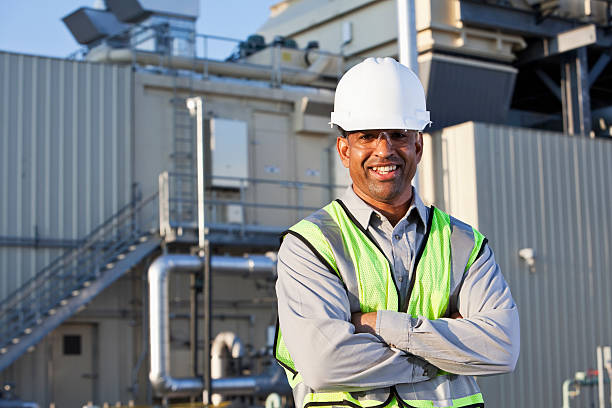 Engineer standing near power generator Portrait of male African American worker (50s) standing near power generator. power plant workers stock pictures, royalty-free photos & images