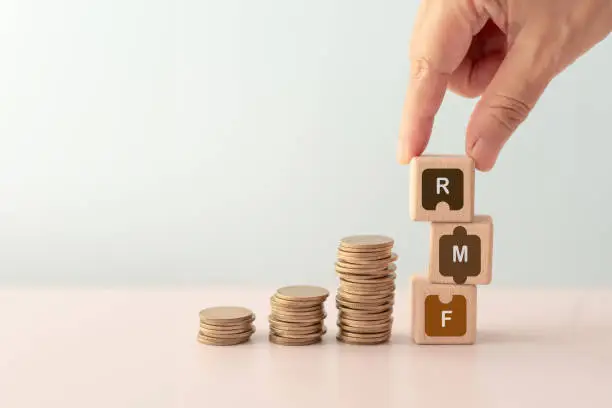 RMF abbreviation for Retirement Mutual Fund, hand completed RMF in jigsaw icon on wooden cube block and  stack of coin. For saving money for prepare in future and pension retirement concept
