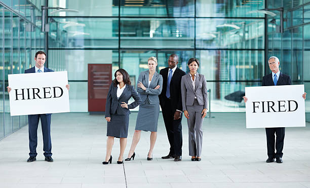 istock Confused business people holding 'hired' and 'fired' boards 184623050