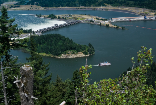 Overhead view of part of Bonniville Dam spillway in Oregon and Washington in the Columbia River Gorge. Tourist paddle boat on rive in forground. Additional Columbia River Gorge photos: