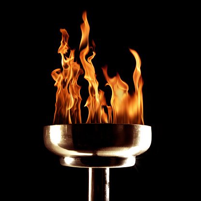 close up shot of burning flaming torch on black background.