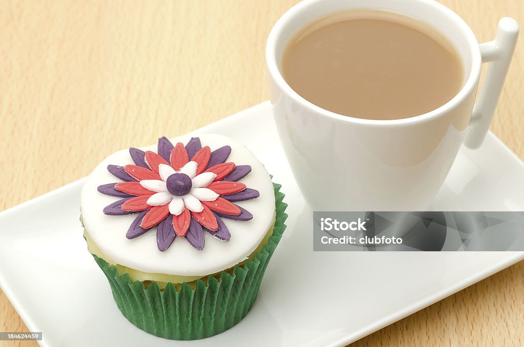 cupcake ghiacciato con una tazza di tè - Foto stock royalty-free di Cibi e bevande