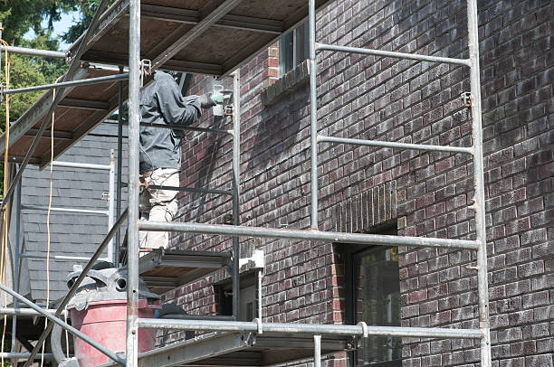 istock Man removing old mortar from side of brick house 184624558