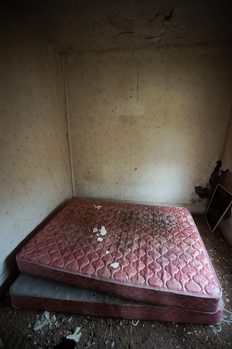 A bedroom in an abandoned house with an old double bed.