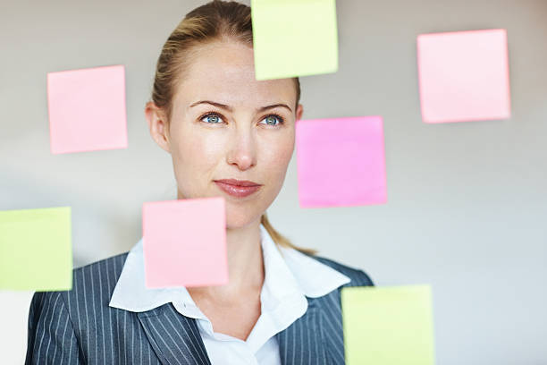 istock Business woman reading adhesive notes on glass window 184625861