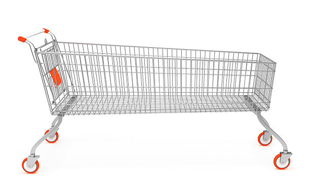 An abandoned shopping cart stands on the grass under a tree in an urban area, near a parking lot and scattered trash.