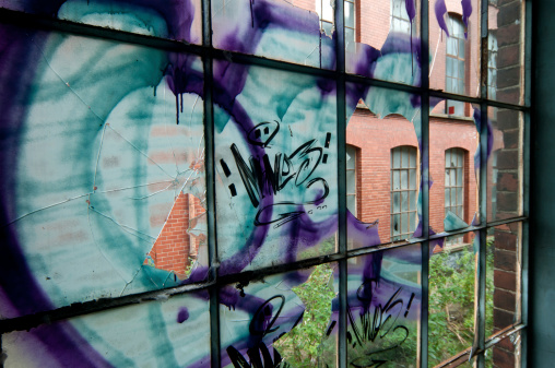 Broken window with graffiti in derelict factory