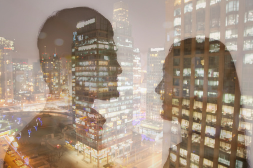 Double exposure of young couple over night cityscape