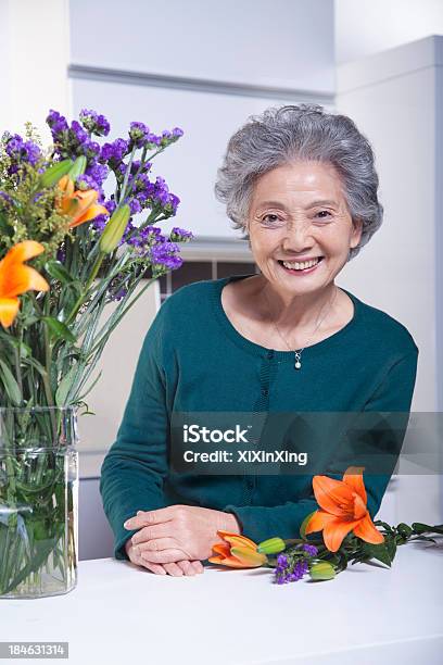 Starszy Kobieta Obok Bukiet Kwiatów W Kuchni Portret - zdjęcia stockowe i więcej obrazów Rozpinany sweter