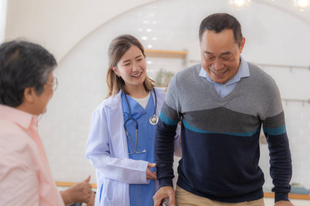 istock Asian young nurse support senior older man walk with walker. Beautiful nurse help and take care. elderly mature grandpa patient doing physical therapy with a group of senior friends in hospital. 1846366440