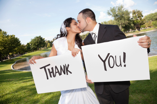 Hispanic Wedding Couple Kissing and Holding Thank You Signs.