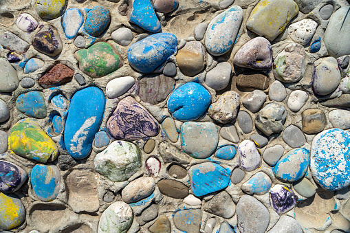 Surface, texture of stones of different sizes, connected in wall pattern, Pebbles painted with colored paint yellow, blue color of old mosaic decoration Shabby pebbles creative decoration, art therapy