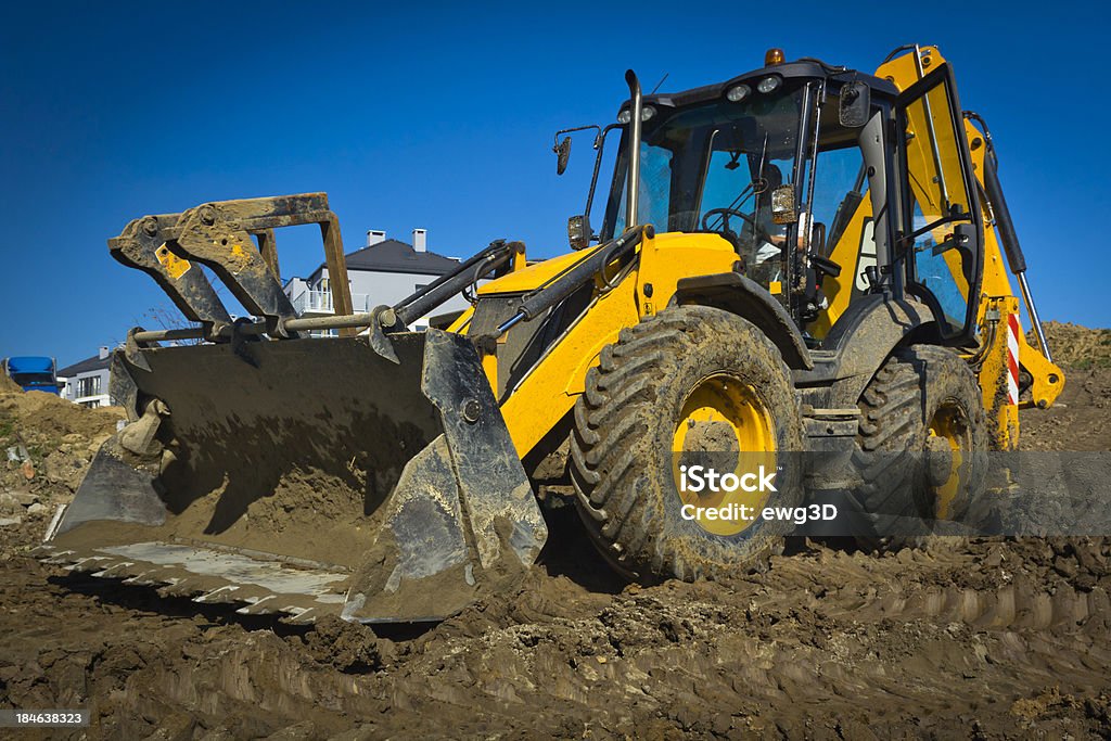 Earth mover working in a new road construction The backhoe at work against blue skySee more CONSTRUCTION MACHINERY images here: Bulldozer Stock Photo