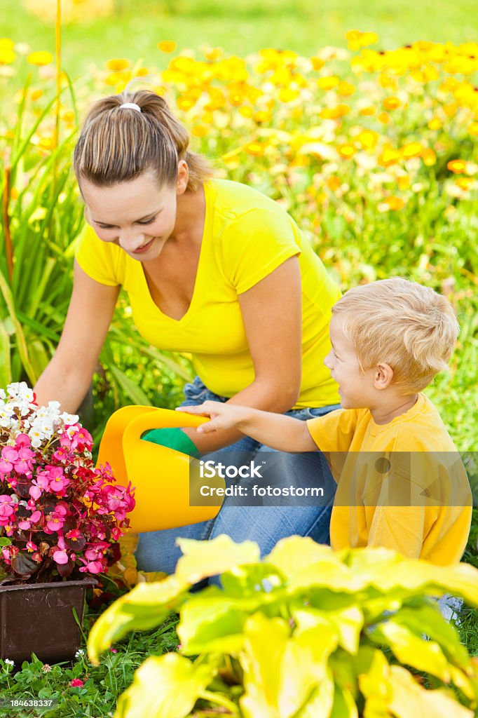 Mother And Son Gardening Smiling young mother and her son gardening outdoors. Adult Stock Photo