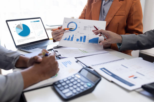 istock Confident business people point to graphs and charts to analyze marketing data graph chart document, balance sheet, account, net profit to plan new sales strategies to increase production capacity. 1846385213