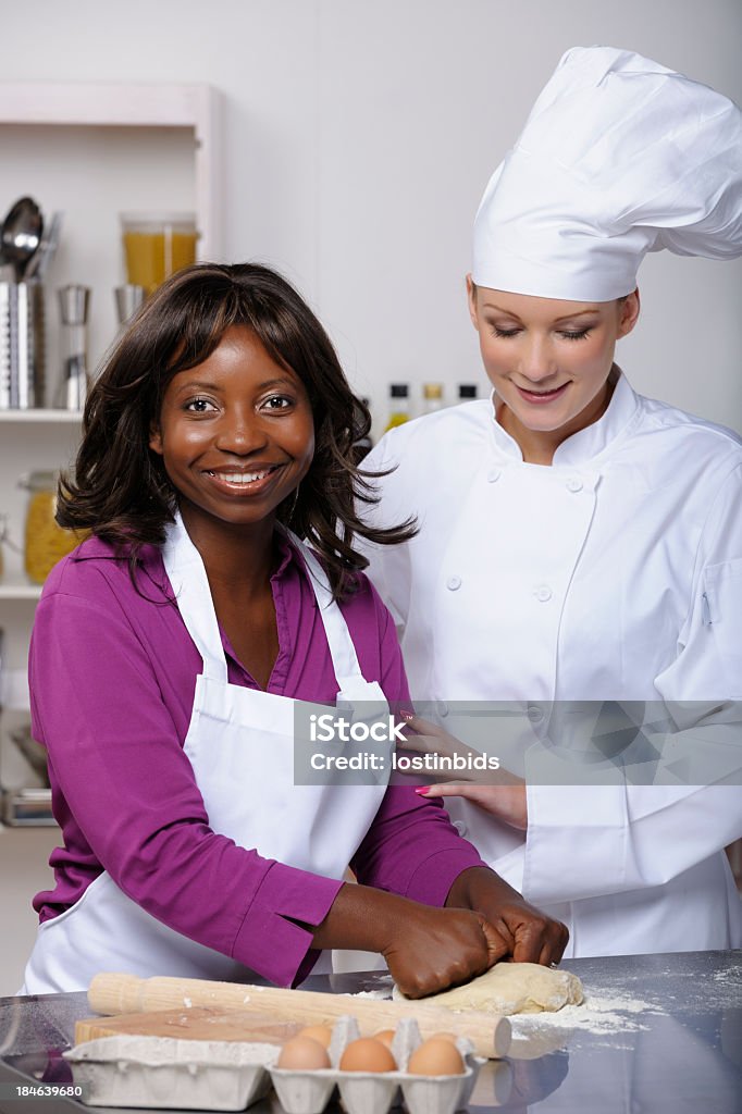 Appentice/ Student Being Encouraged By Chef/ Instructor Portrait of a chef/ cooking instructor encouraging appentice/ student in a professional kitchen. 20-29 Years Stock Photo