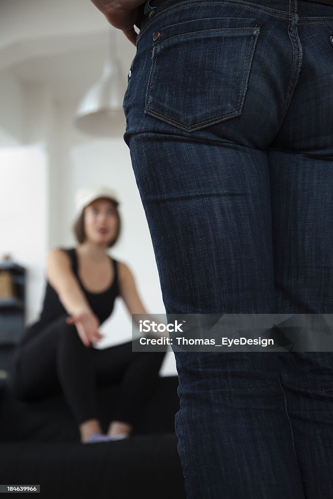 Gay Couple sitting on couch having a heated argument "Young Lesbian couple sitting on a couch in heated argument, low angle view. Vertical,  shot." Arguing Stock Photo