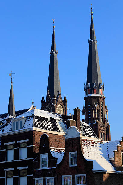 monumental houses in front of Delft's Maria van Jessekerk "monumental houses on the Markt with the characteristic towers of the Maria van Jessekerk in the background; Delft, Netherlands" delft winter netherlands snow stock pictures, royalty-free photos & images