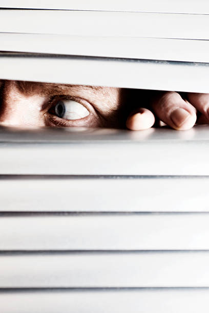 istock Nervous man looks sideways behind venetian blind 184640396