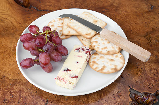 assiette de fromage de wensleydale avec des canneberges, des biscuits salés et de raisin rouge - wensleydale photos et images de collection