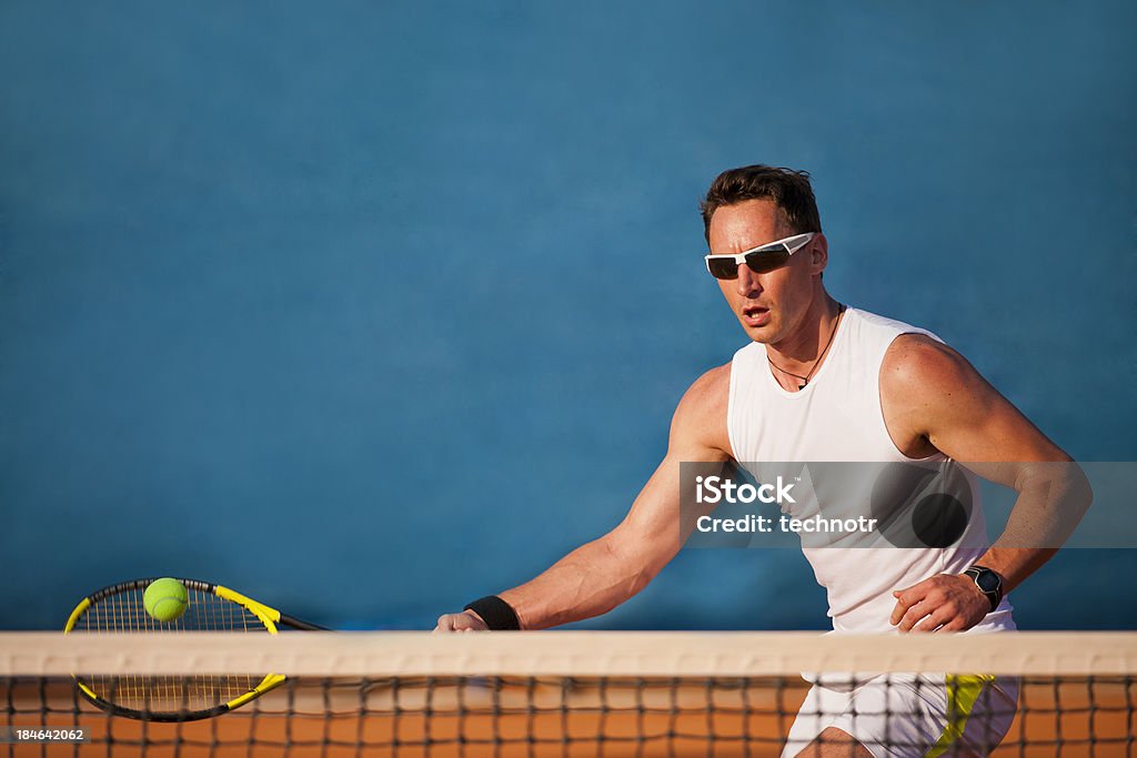 Tennis player on the blue background Front view of male tennis player at forehand volley 20-24 Years Stock Photo