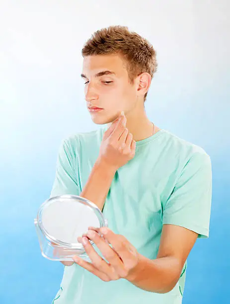 Photo of Teenage boy applying cleaning patch to a pimple.