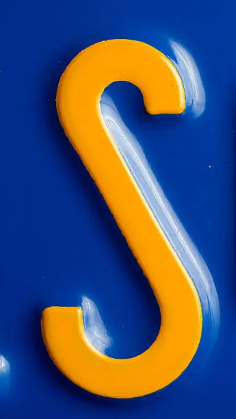 S letter. Part of an old  outdated blue license plate (80ties) from California. The complete plate number is not recognizable.