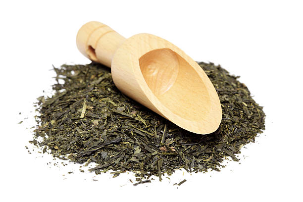Green tea leaves and wooden spoon isolated on white