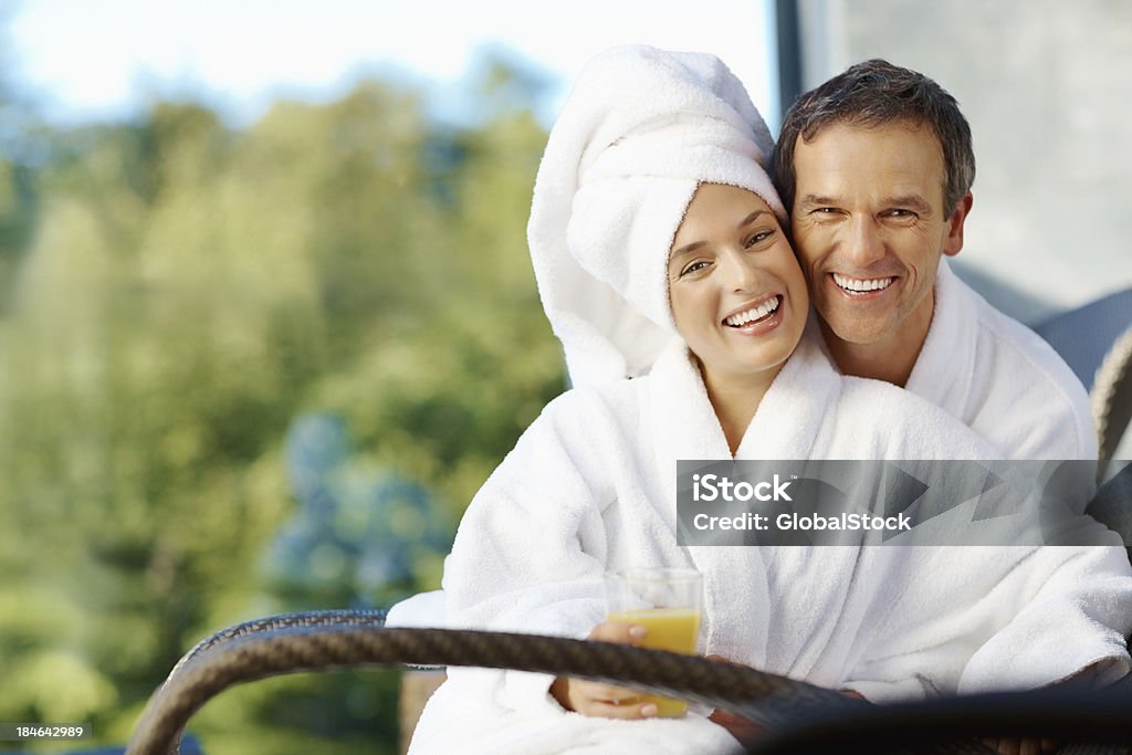 Coppia sorridente seduto all'aperto, avvolti in asciugamani - Foto stock royalty-free di Relazione di coppia