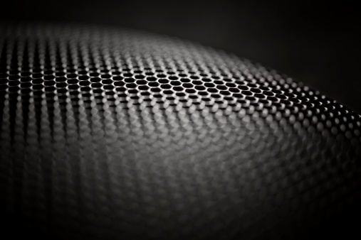 Black metal speaker grille with very shallow depth of field.