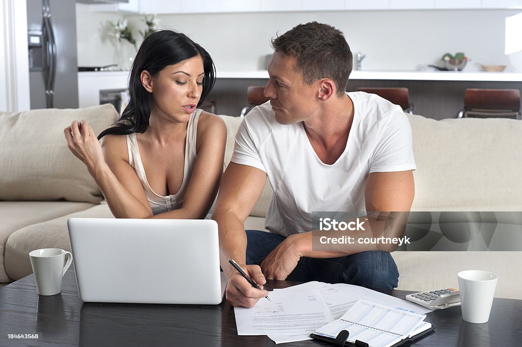 Couple doing paperwork with a laptop computer Couple doing paperwork with a laptop computer on the sofa 25-29 Years Stock Photo