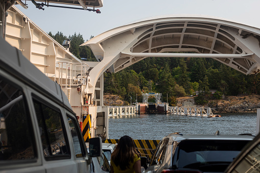 Pender Island, Canada - August 19, 2023. A ferry arrives at the terminal on Pender Island; the deck opens to allow vehicles off.