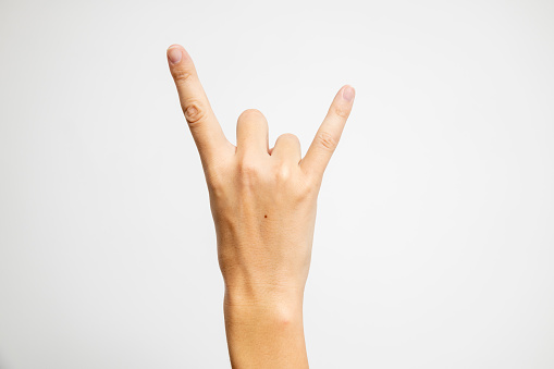 The iconic Rock and Roll hand symbol, featuring a raised clenched fist with extended index and pinky fingers, is boldly displayed on a crisp white background.