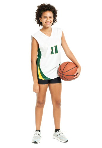 An unrecognizable young basketball kid is dribbling a ball and practicing tricks with basketball on training at indoor court. Cropped dynamic picture of a junior basketball player practicing on court.