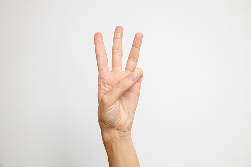 A hand displaying three fingers, specifically the index, middle, and ring fingers, against a clean white background.
