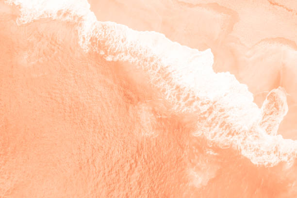 Sea waves and beach trending color of year 2024 Peach Fuzz. stock photo