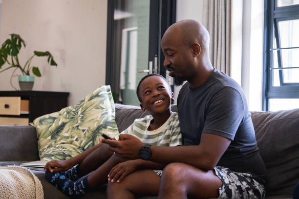 istock Father and son enjoy sitting on the sofa watching TV together 1846460581