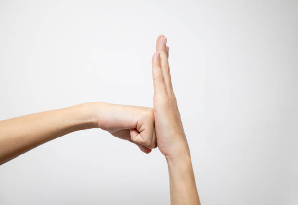 The fist is gently cradled against the open palm, creating a harmonious gesture, on a white background.
