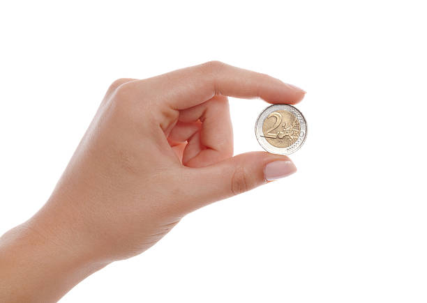 moneta dwa euro w kobieta ręką na białym tle - european union coin european union currency coin euro symbol zdjęcia i obrazy z banku zdjęć